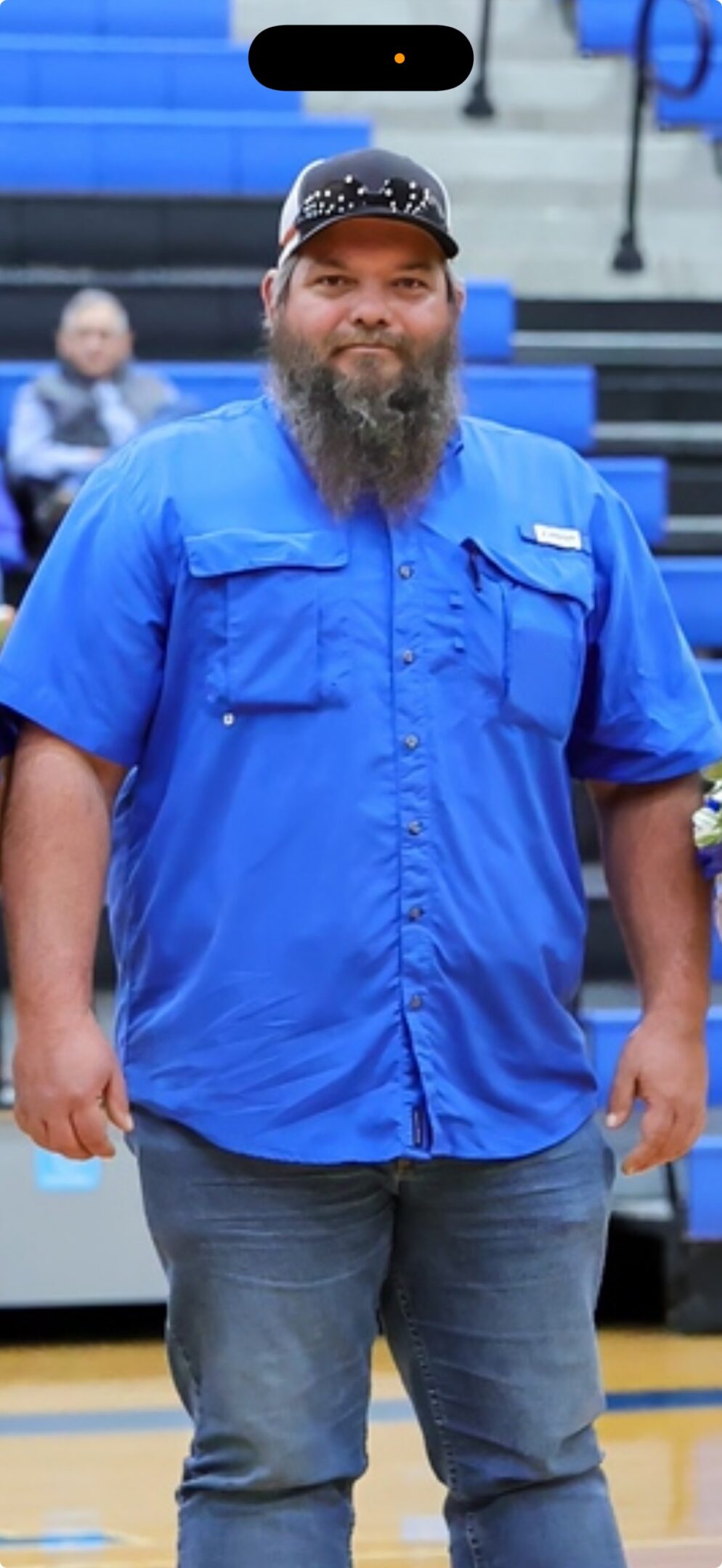 Man wearing a blue work shirt with beard.
