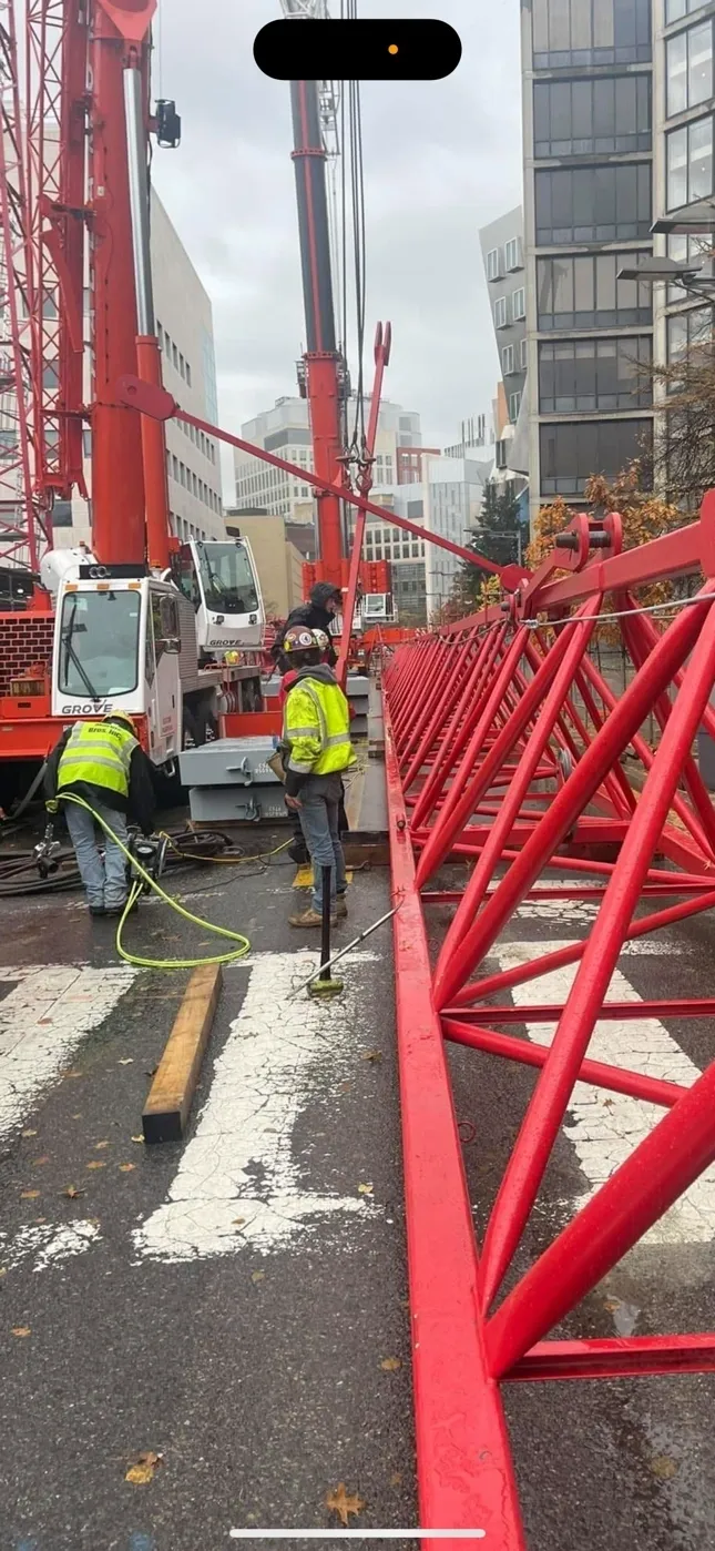 Workers assembling large red construction crane.