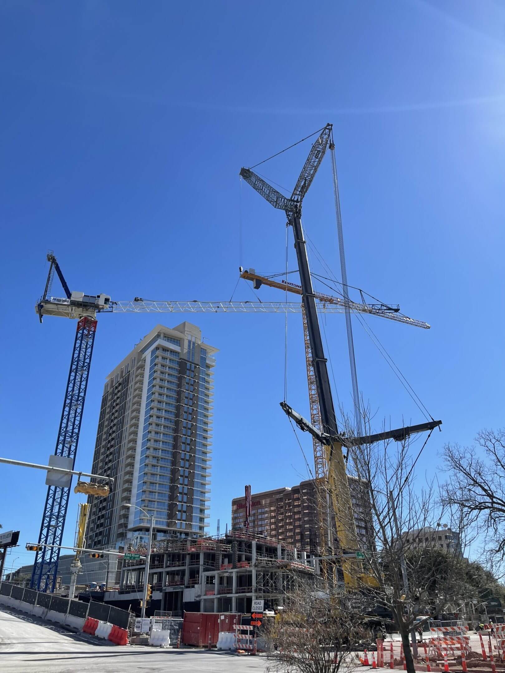 Two large cranes towering over a city construction site on a clear day.