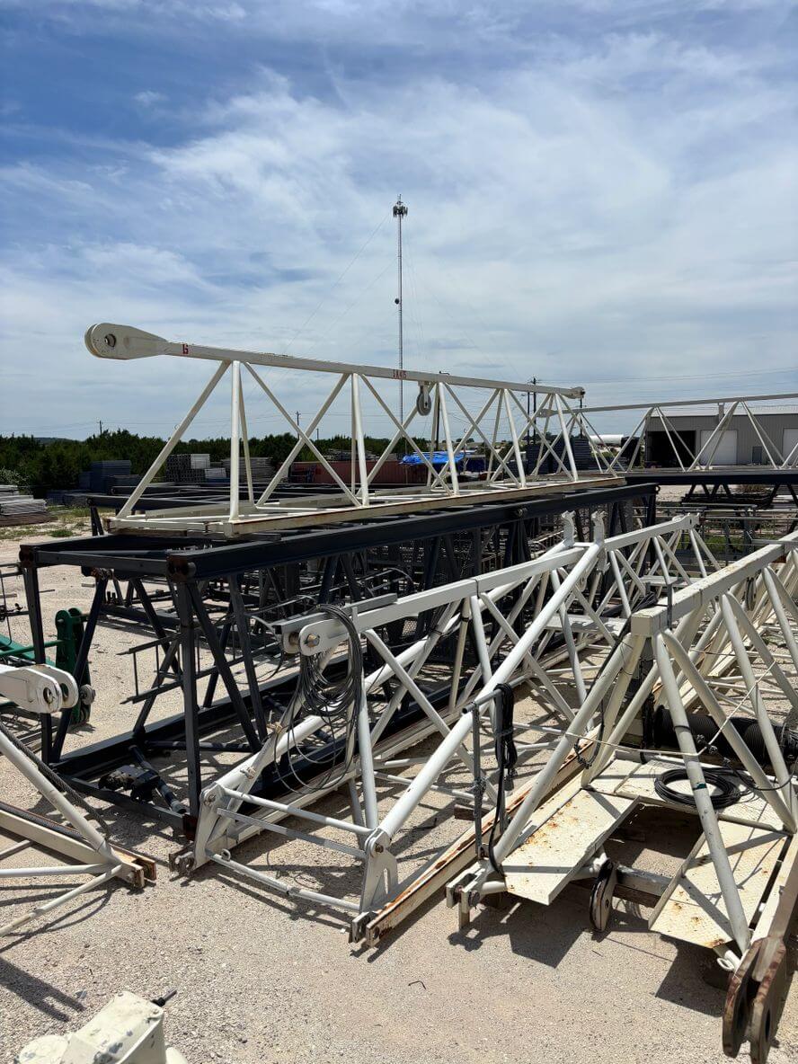 Metal truss structures stacked outdoors under a cloudy sky.