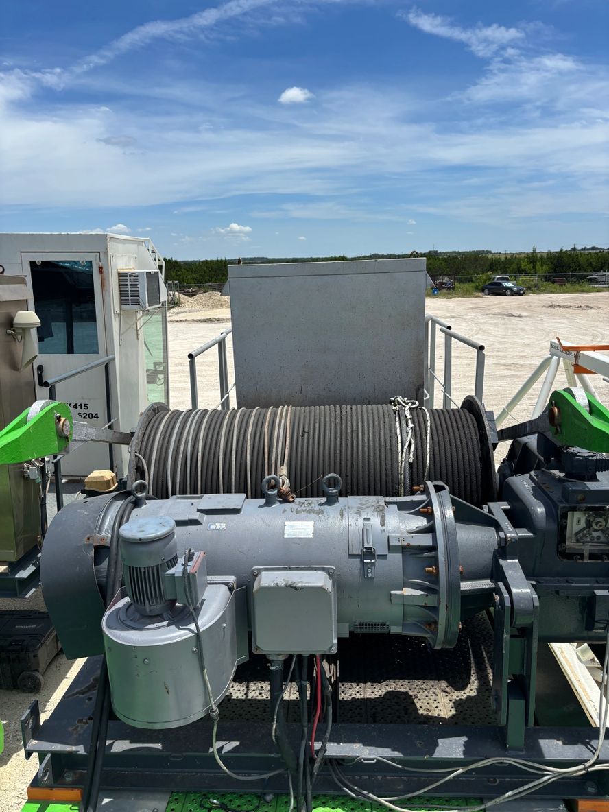 Industrial machinery with hoses and control panel under a partly cloudy sky.