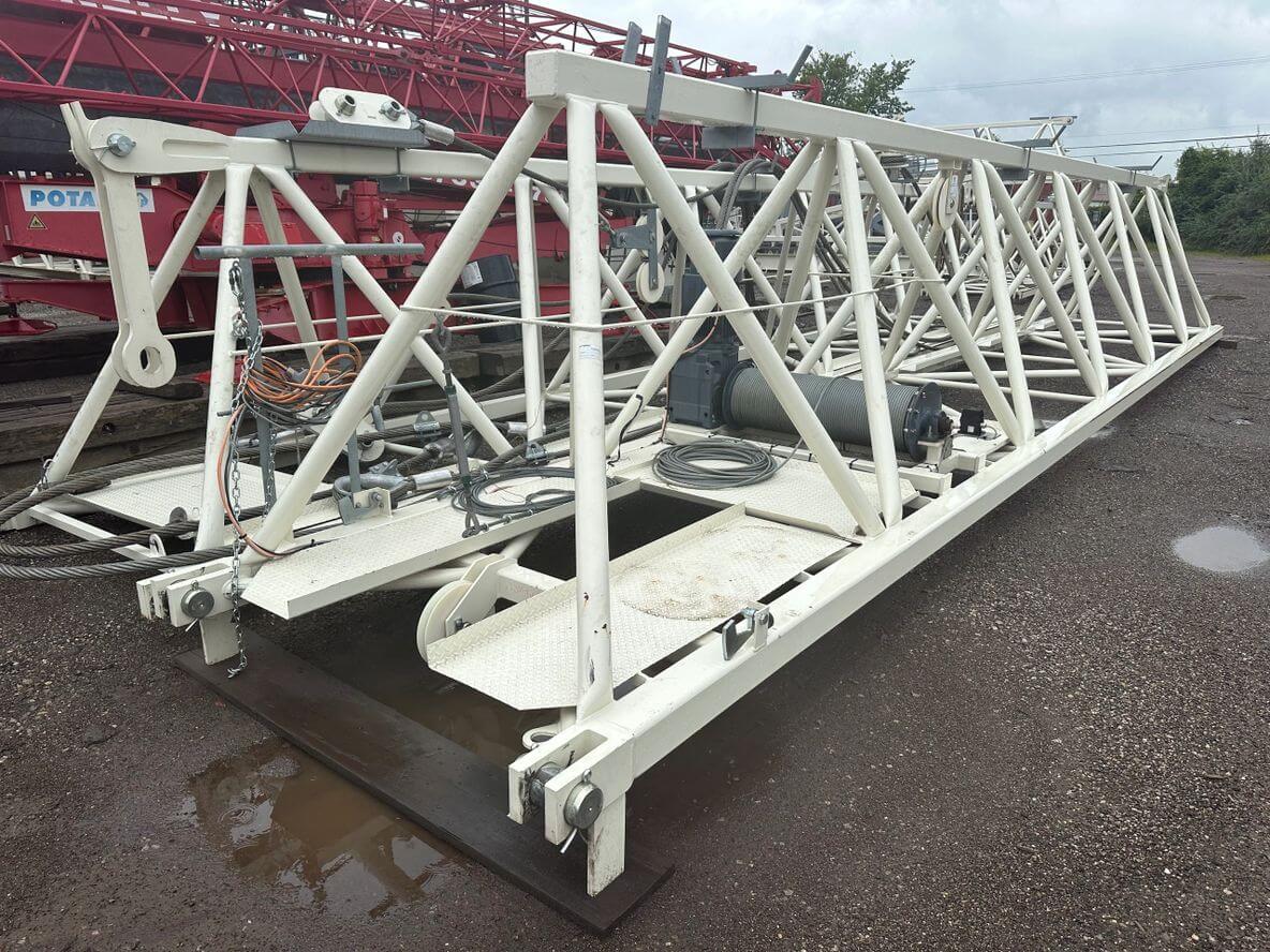 A large white metal truss structure resting on the ground outdoors.