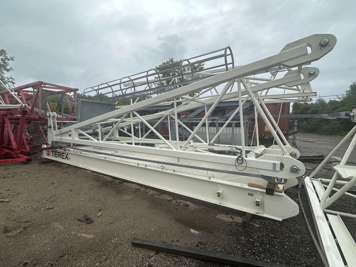 Large white metal truss structure lying on the ground outdoors.