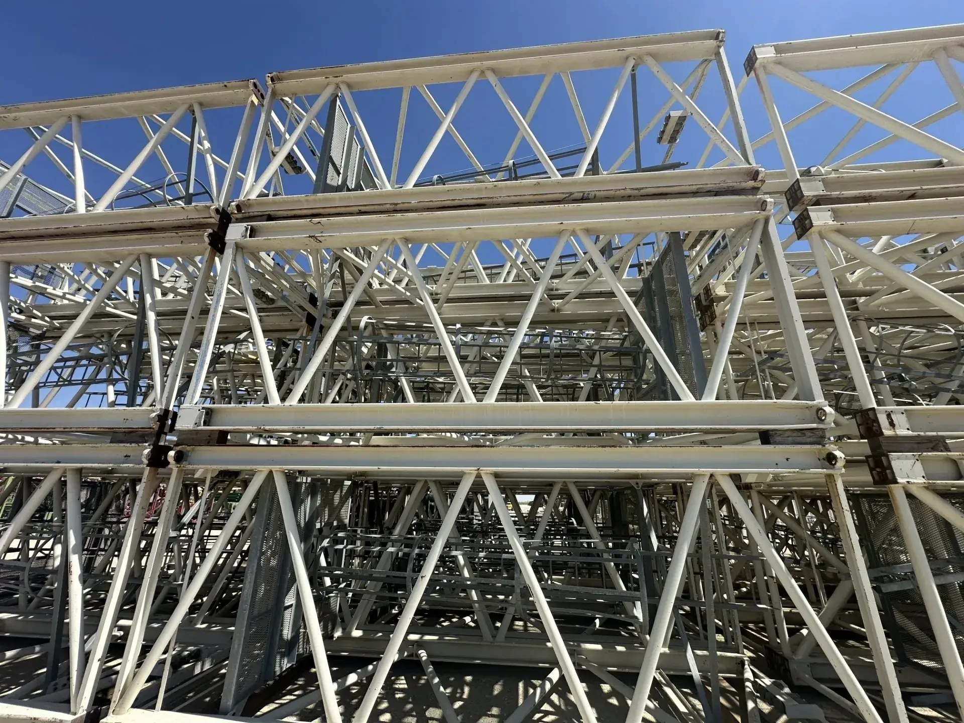 Stacked metal scaffolding under clear blue sky.