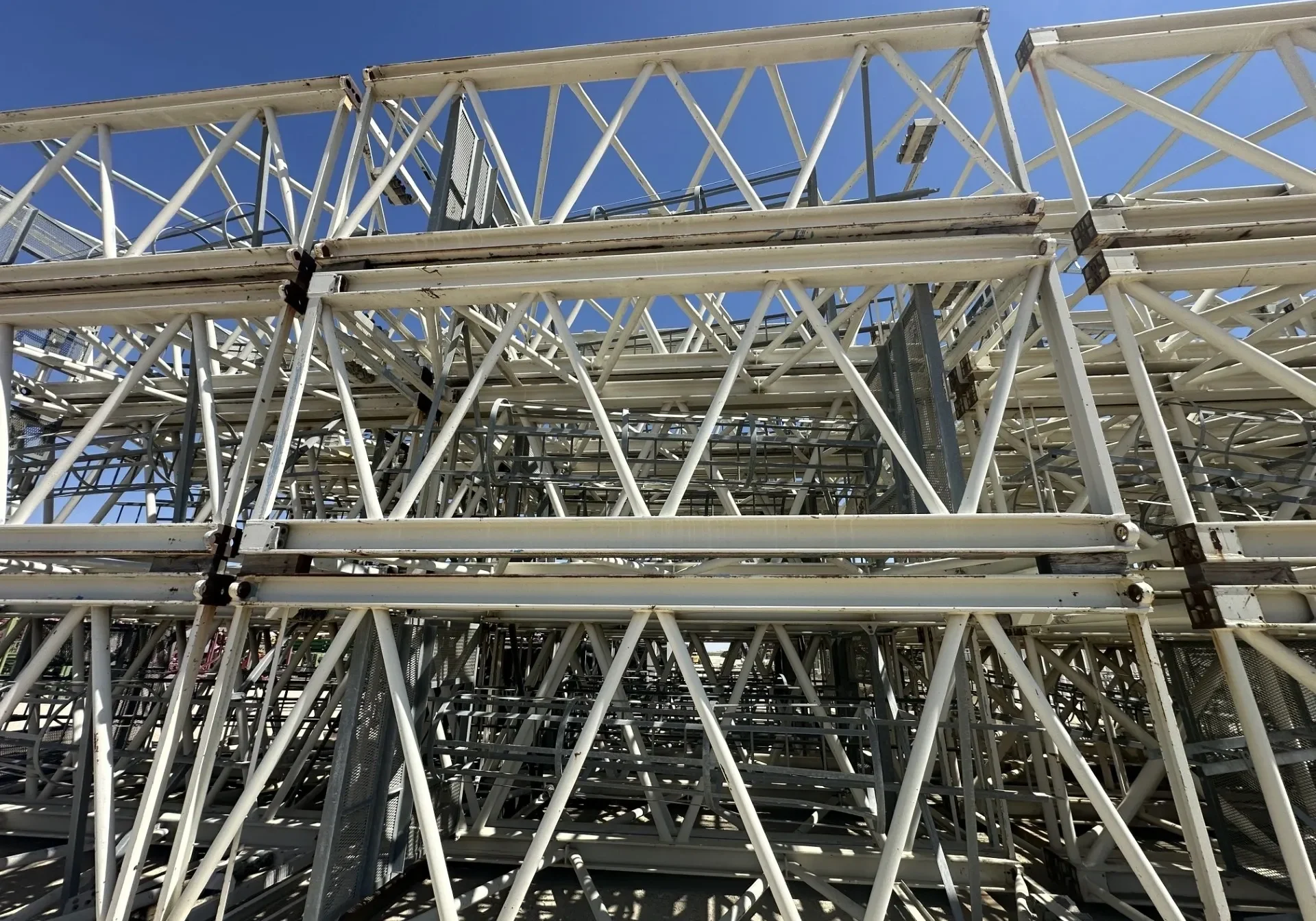 Stacked metal scaffolding under clear blue sky.